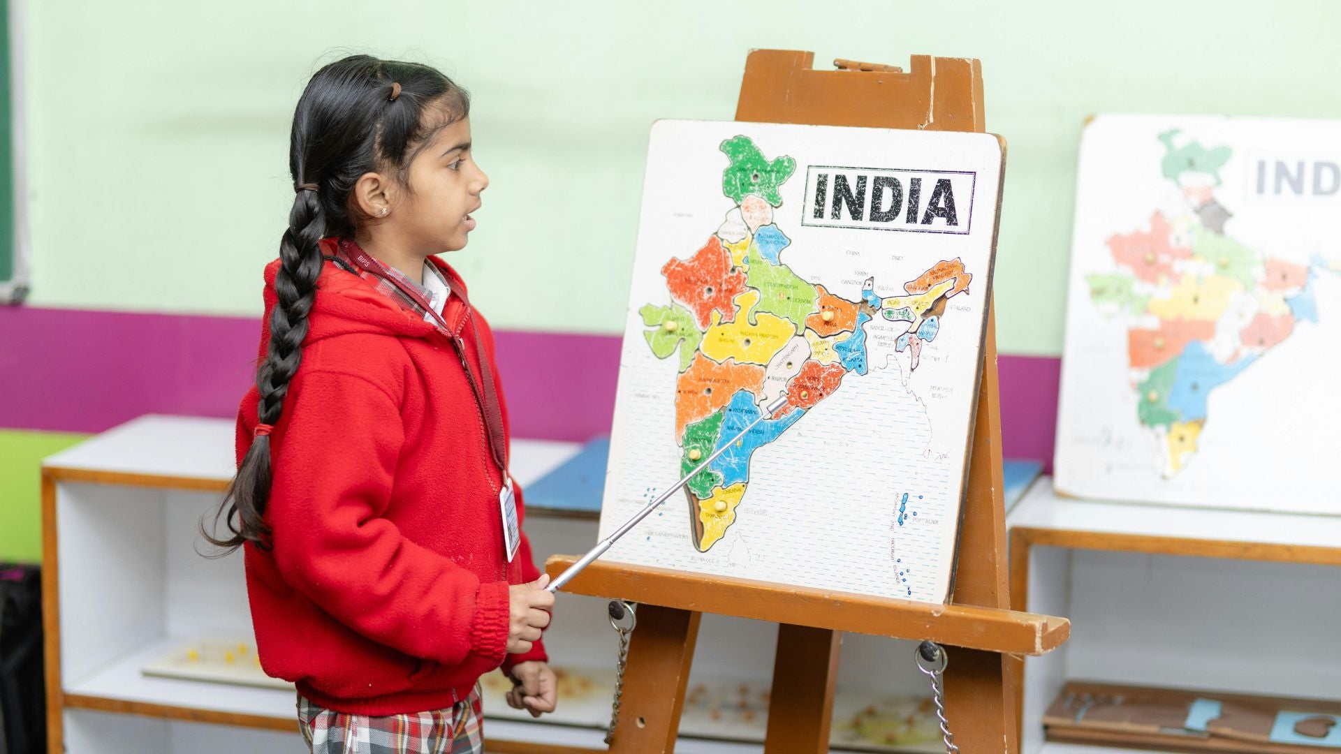 Child in a classroom with a map of India on an easel